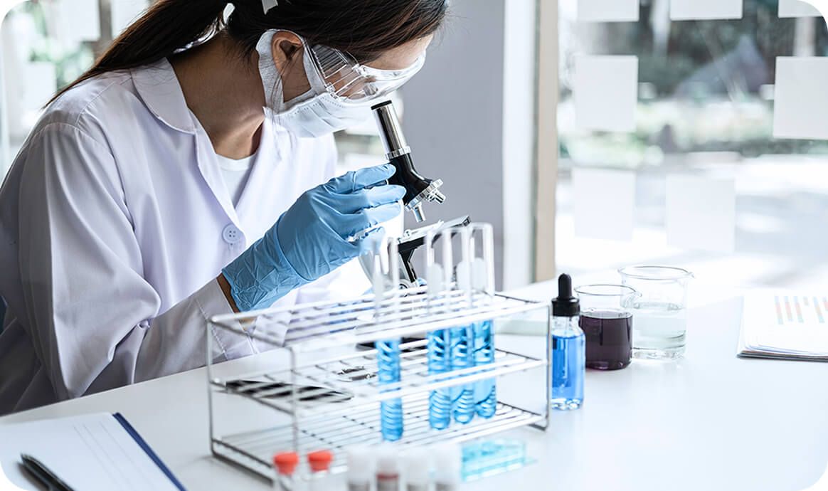 Scientist with microscope and test tubes.